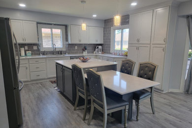 Mid-sized contemporary kitchen in Detroit with an undermount sink, grey cabinets, quartzite benchtops, subway tile splashback, stainless steel appliances, vinyl floors, grey floor and white benchtop.