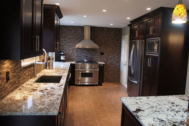 Example of a mid-sized classic u-shaped ceramic tile and brown floor enclosed kitchen design in Vancouver with an undermount sink, recessed-panel cabinets, dark wood cabinets, granite countertops, brown backsplash, mosaic tile backsplash, stainless steel appliances and no island