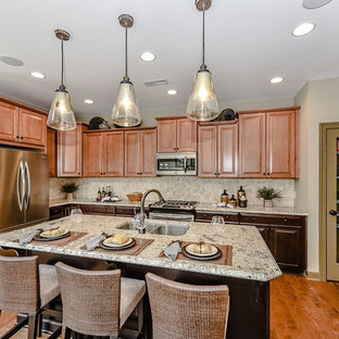 Выдающиеся фото от архитекторов и дизайнеров интерьера: маленькая угловая кухня-гостиная в классическом стиле с двойной раковиной, фасадами с выступающей филенкой, коричневыми фасадами, столешницей из гранита, разноцветным фартуком, фартуком из плитки мозаики, техникой из нержавеющей стали, светлым паркетным полом и островом