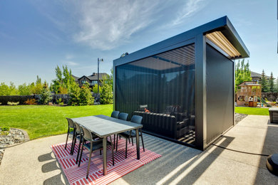 Modern back ground level terrace in Calgary with a pergola.