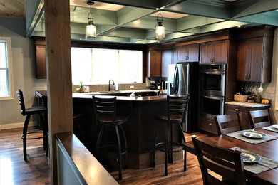 Example of a large arts and crafts l-shaped dark wood floor and brown floor eat-in kitchen design in Boston with a drop-in sink, shaker cabinets, distressed cabinets, granite countertops, gray backsplash, stone slab backsplash, stainless steel appliances and an island