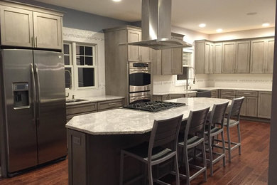 Eat-in kitchen - large transitional l-shaped medium tone wood floor eat-in kitchen idea in Grand Rapids with a farmhouse sink, shaker cabinets, gray cabinets, quartz countertops, white backsplash, porcelain backsplash, stainless steel appliances and an island