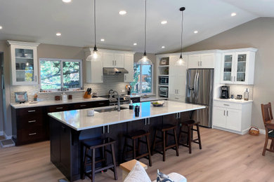 Inspiration for a large transitional l-shaped vinyl floor, beige floor and vaulted ceiling open concept kitchen remodel in Denver with a single-bowl sink, shaker cabinets, quartz countertops, gray backsplash, glass sheet backsplash, stainless steel appliances and an island