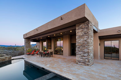 Mid-sized mountain style backyard stone patio photo in Phoenix with a fire pit and a roof extension