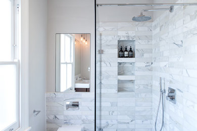 This is an example of a mid-sized contemporary 3/4 bathroom in London with an open shower, white tile, stone tile, white walls, marble floors, a one-piece toilet and an open shower.