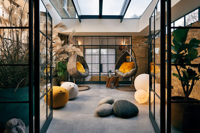Photo of a large contemporary sunroom in London with porcelain floors, a glass ceiling and grey floor.