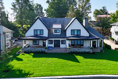 Inspiration for a huge transitional white two-story vinyl house exterior remodel in Other with a mixed material roof and a black roof