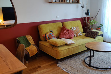 Foto de salón cerrado contemporáneo pequeño sin chimenea con paredes rojas, suelo de madera clara y televisor colgado en la pared