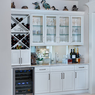 マイアミの中サイズのトランジショナルスタイルのおしゃれなウェットバー (アンダーカウンターシンク、レイズドパネル扉のキャビネット、白いキャビネット、珪岩カウンター、ミラータイルのキッチンパネル、ライムストーンの床、ベージュの床、白いキッチンカウンター) の写真