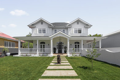 Aménagement d'une grande façade de maison blanche classique à un étage avec un toit à deux pans, un toit en shingle et un toit gris.