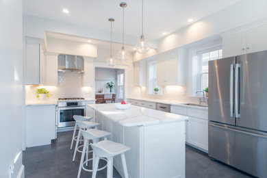 Photo of a mid-sized contemporary l-shaped separate kitchen in Boston with a drop-in sink, shaker cabinets, white cabinets, quartz benchtops, white splashback, ceramic splashback, stainless steel appliances, ceramic floors, with island, grey floor and white benchtop.