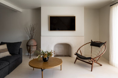 Inspiration for a mediterranean white floor family room remodel in Los Angeles with white walls, a standard fireplace and a wall-mounted tv