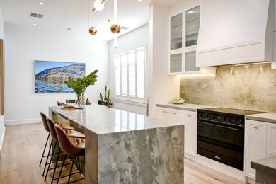 Large contemporary galley eat-in kitchen in Sydney with a farmhouse sink, shaker cabinets, white cabinets, marble benchtops, green splashback, marble splashback, black appliances, light hardwood floors, with island, brown floor and green benchtop.