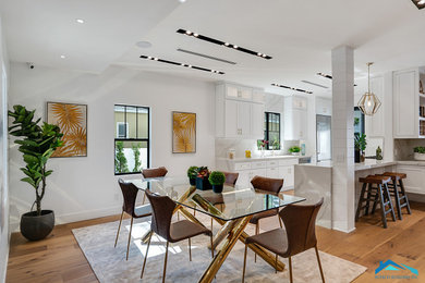 Photo of a large contemporary kitchen/dining room in Los Angeles with white walls, medium hardwood flooring and brown floors.