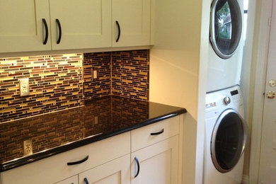 Inspiration for a small eclectic l-shaped medium tone wood floor laundry room remodel in Austin with shaker cabinets, white cabinets, granite countertops, a stacked washer/dryer and beige walls
