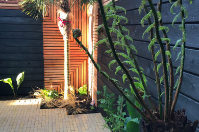 This is an example of a small contemporary back private partial sun garden for summer in Surrey with natural stone paving.