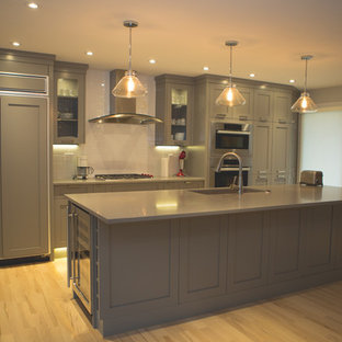 Moderne Küche mit Vorratsschrank, Unterbauwaschbecken, Schrankfronten im Shaker-Stil, grauen Schränken, Kalkstein-Arbeitsplatte, weißen Elektrogeräten, hellem Holzboden und Kücheninsel in Calgary