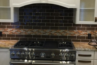 Inspiration for a mid-sized timeless l-shaped medium tone wood floor and brown floor enclosed kitchen remodel in Other with an undermount sink, recessed-panel cabinets, white cabinets, granite countertops, brown backsplash, glass tile backsplash and stainless steel appliances