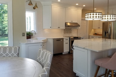 Eat-in kitchen - large transitional u-shaped medium tone wood floor and gray floor eat-in kitchen idea in Other with a farmhouse sink, shaker cabinets, white cabinets, quartz countertops, white backsplash, subway tile backsplash, stainless steel appliances, an island and white countertops