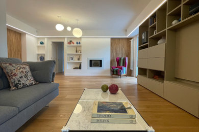 Esempio di un grande soggiorno design aperto con libreria, pareti bianche, parquet scuro, camino sospeso, parete attrezzata e pavimento marrone