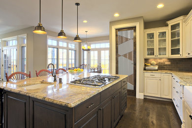 L-shaped medium tone wood floor eat-in kitchen photo in Other with a farmhouse sink, raised-panel cabinets, dark wood cabinets, granite countertops, brown backsplash and subway tile backsplash