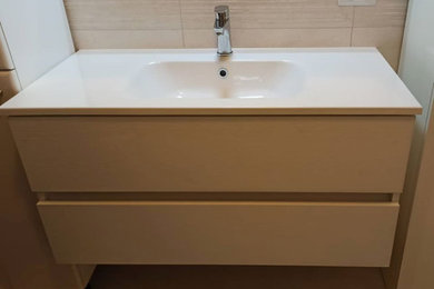 Ispirazione per una stanza da bagno con doccia minimal di medie dimensioni con doccia ad angolo, WC sospeso, piastrelle beige, pareti beige, lavabo integrato, top in superficie solida, pavimento beige, porta doccia scorrevole e top bianco