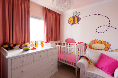 テルアビブにあるお手頃価格の小さなコンテンポラリースタイルのおしゃれな赤ちゃん部屋 (ピンクの壁、無垢フローリング、ベージュの床、壁紙、照明) の写真