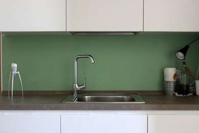 ボローニャにある低価格の小さなエクレクティックスタイルのおしゃれなキッチン (ドロップインシンク、フラットパネル扉のキャビネット、白いキャビネット、ラミネートカウンター、緑のキッチンパネル、グレーのキッチンカウンター) の写真