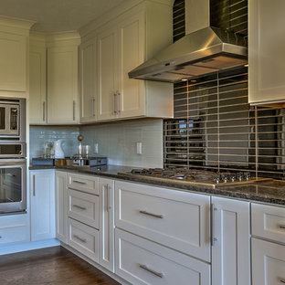 Transitional kitchen pantry remodeling - Transitional l-shaped medium tone wood floor kitchen pantry photo in Omaha with an undermount sink, shaker cabinets, white cabinets, granite countertops, black backsplash, glass tile backsplash, stainless steel appliances and an island