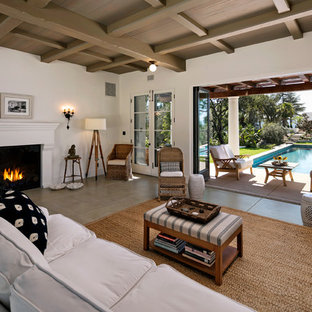 Modelo de salón abierto, mediterráneo, pequeño, con paredes blancas, suelo de cemento, chimenea tradicional y marco de chimenea de yeso