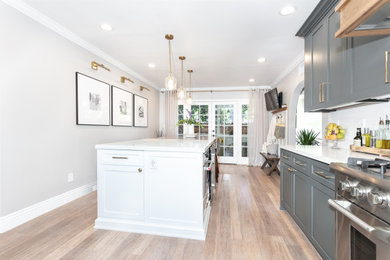 Example of a mid-sized bamboo floor eat-in kitchen design in Los Angeles with recessed-panel cabinets, an island, quartz countertops and quartz backsplash