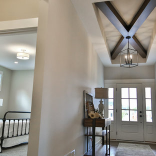 Idee per un ingresso country di medie dimensioni con pareti beige, pavimento in laminato, una porta singola, una porta bianca e pavimento marrone