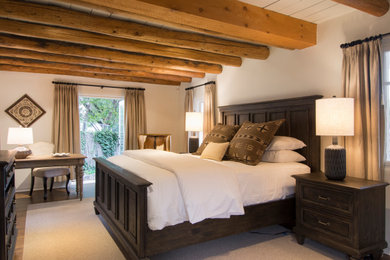 Modelo de dormitorio principal tradicional renovado sin chimenea con paredes blancas, suelo de madera en tonos medios, suelo marrón y vigas vistas