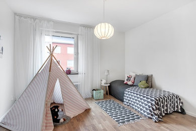 Photo of a mid-sized scandinavian bedroom in Stockholm with white walls and painted wood floors.