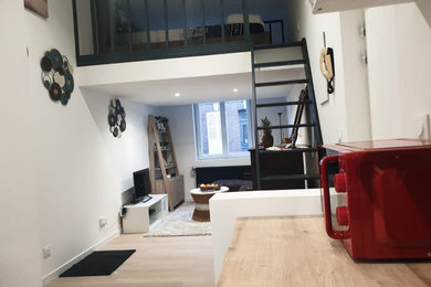 Cette image montre un petit salon mansardé ou avec mezzanine beige et blanc minimaliste avec un sol en contreplaqué, aucune cheminée et un escalier.