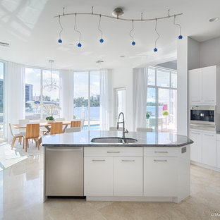 Idéer för ett maritimt kök, med släta luckor, vita skåp, granitbänkskiva, grått stänkskydd, stänkskydd i metallkakel, rostfria vitvaror, cementgolv, en köksö och beiget golv