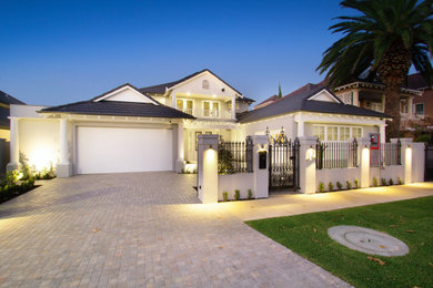 Large traditional two-storey stucco grey house exterior in Other with a clipped gable roof and a tile roof.