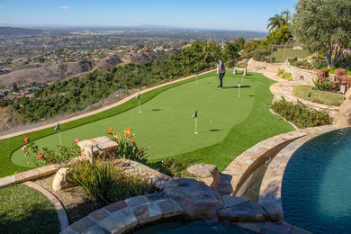 Inspiration for a large tropical full sun backyard stone landscaping in Orange County.