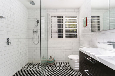 Design ideas for a mid-sized contemporary 3/4 bathroom in Sydney with flat-panel cabinets, an alcove shower, white tile, white walls, an open shower, white benchtops, black cabinets, a two-piece toilet, subway tile, a wall-mount sink and black floor.