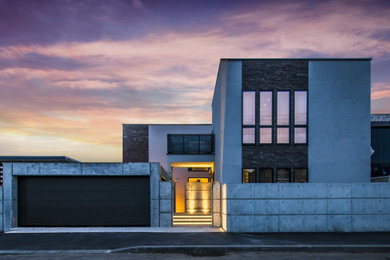 Imagen de fachada de casa gris y gris minimalista grande de dos plantas con revestimiento de piedra, tejado plano y tejado de metal