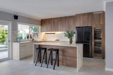 This is an example of a large scandinavian l-shaped open plan kitchen in Sydney with an undermount sink, flat-panel cabinets, solid surface benchtops, white splashback, porcelain splashback, black appliances, porcelain floors, with island, grey floor and white benchtop.