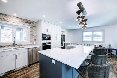 Example of a large trendy l-shaped brown floor open concept kitchen design in Calgary with a single-bowl sink, flat-panel cabinets, white cabinets, marble countertops, stone tile backsplash, stainless steel appliances, an island and white countertops