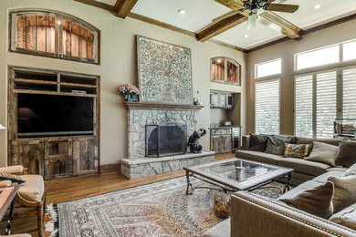 Inspiration for a large transitional formal enclosed living room in Dallas with beige walls, medium hardwood floors, a standard fireplace, a stone fireplace surround, a wall-mounted tv and brown floor.