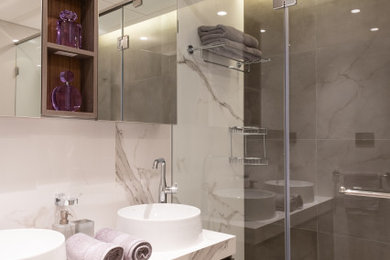 This is an example of a medium sized modern bathroom with flat-panel cabinets, white tiles, marble flooring, a wall-mounted sink, white floors, an open shower and a floating vanity unit.