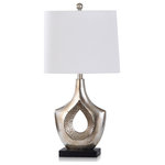 StyleCraft - Contemporary Moulded Table Lamp With Hammered Hollow Center, Black Base, Silver - The Laslo table lamp is a distinctive contemporary fixture with a distressed silver frame, a white drum shade, and a contrasting black base. The molded frame has an open center featuring a hammered textured finish. A living room or family room side table is an ideal spot for this lamp with its unusual shape and silver finish with gold undertones.