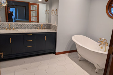 Example of a mid-sized classic master multicolored tile and ceramic tile ceramic tile, white floor and double-sink claw-foot bathtub design in Indianapolis with open cabinets, blue cabinets, blue walls, an integrated sink, marble countertops, gray countertops and a freestanding vanity