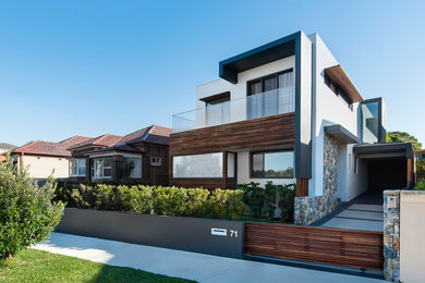 This is an example of a large modern two-storey white exterior in Sydney with stone veneer and a flat roof.
