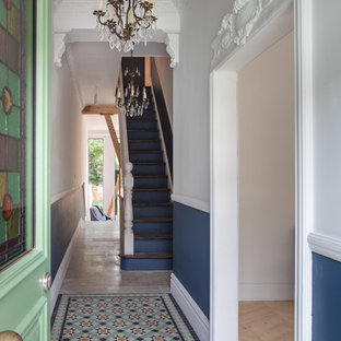 Eklektisk inredning av en hall, med en enkeldörr, en grön dörr, flerfärgade väggar och flerfärgat golv