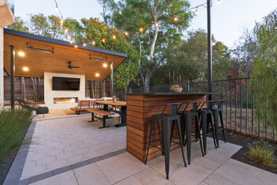 Patio - mid-sized modern backyard concrete paver patio idea in San Luis Obispo with a fireplace and a pergola