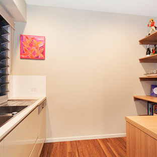 Inredning av ett asiatiskt mellanstort skafferi, med en dubbel diskho, bänkskiva i koppar, rostfria vitvaror, vinylgolv, beige skåp, vitt stänkskydd och stänkskydd i keramik